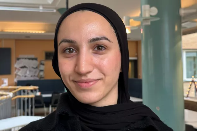 Image of Hanna Chahin dressed in black standing in the lunch room area.