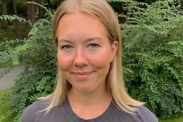 Picture of Matilda Engström standing outside with green bushes in the background.